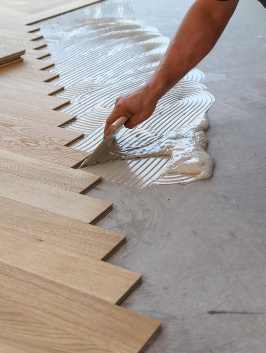 Worker putting the glue on the floor for Wooden flooring purpose