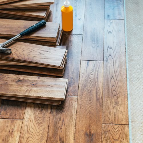 Wooden flooring sheet with glue and hammer on the floor