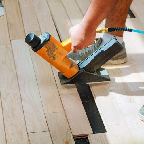 Carpenter fixing wooden blocks on the floor